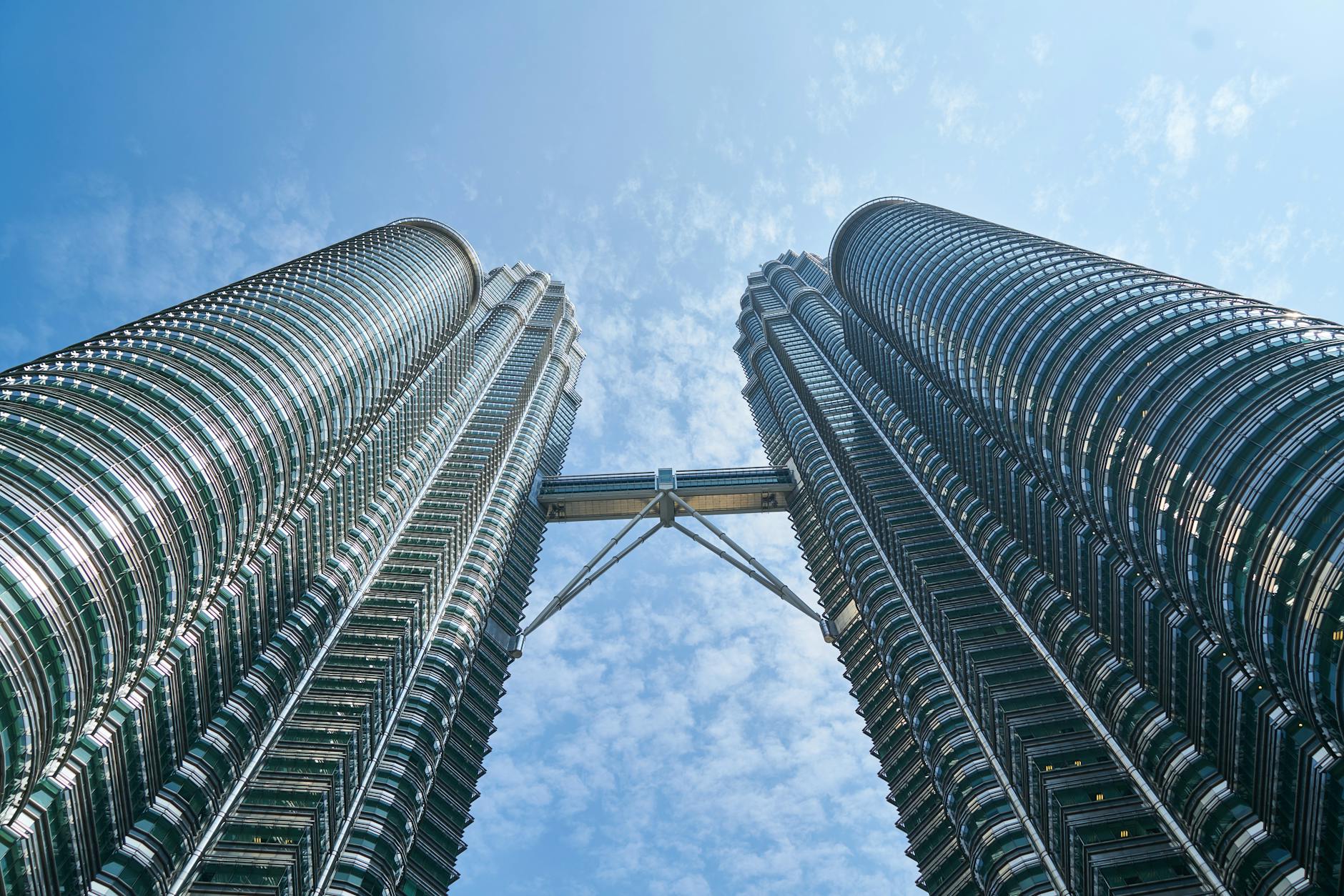View of the iconic Petronas Twin Towers reaching towards a vibrant blue sky in Kuala Lumpur.