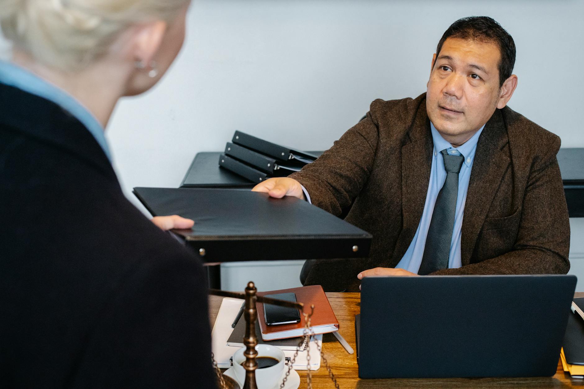 A professional business interaction at a desk with document exchange.