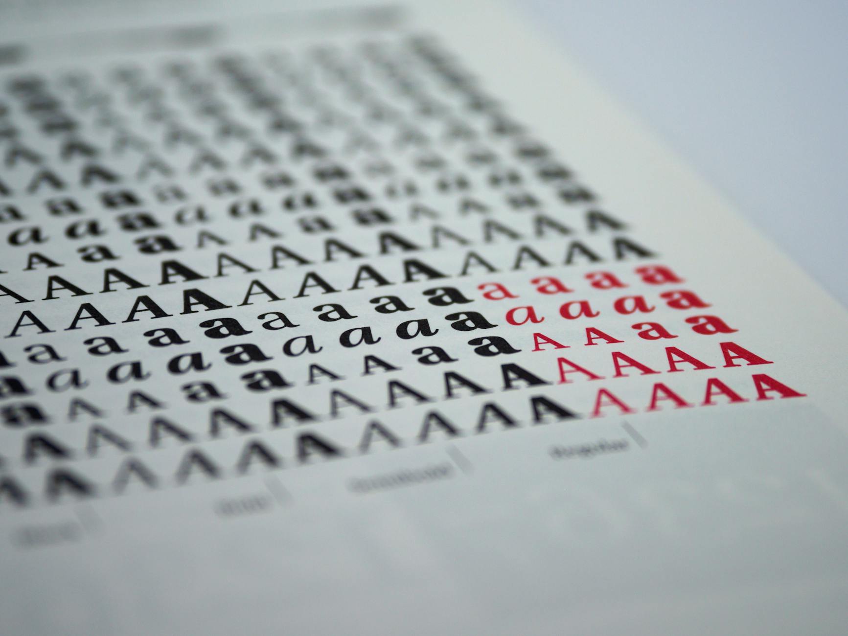 Close-up view of various printed letter 'A' styles in black and red on white paper.