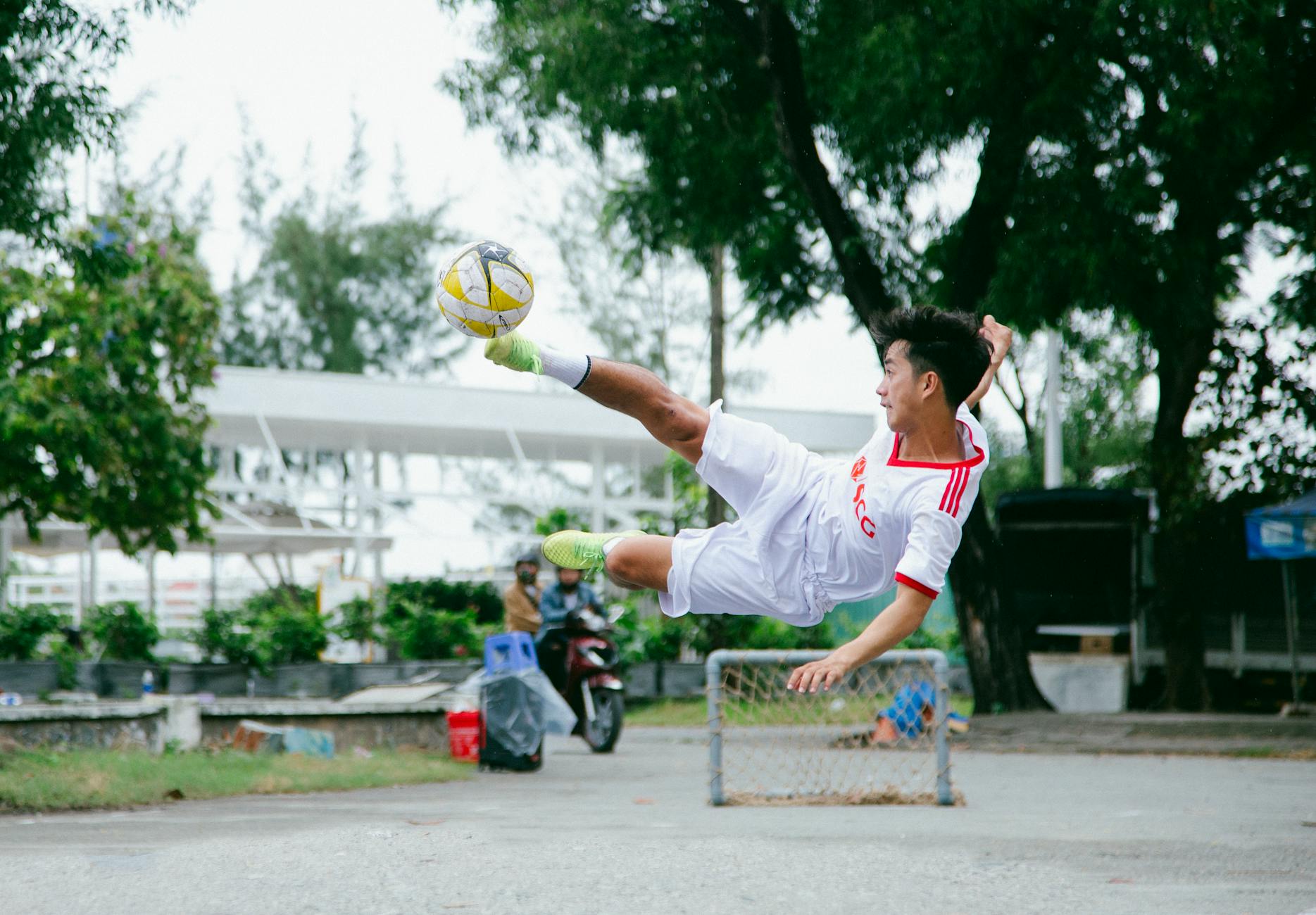 Young Asian male soccer player executing a high jump kick. Energetic and skillful athletic action.