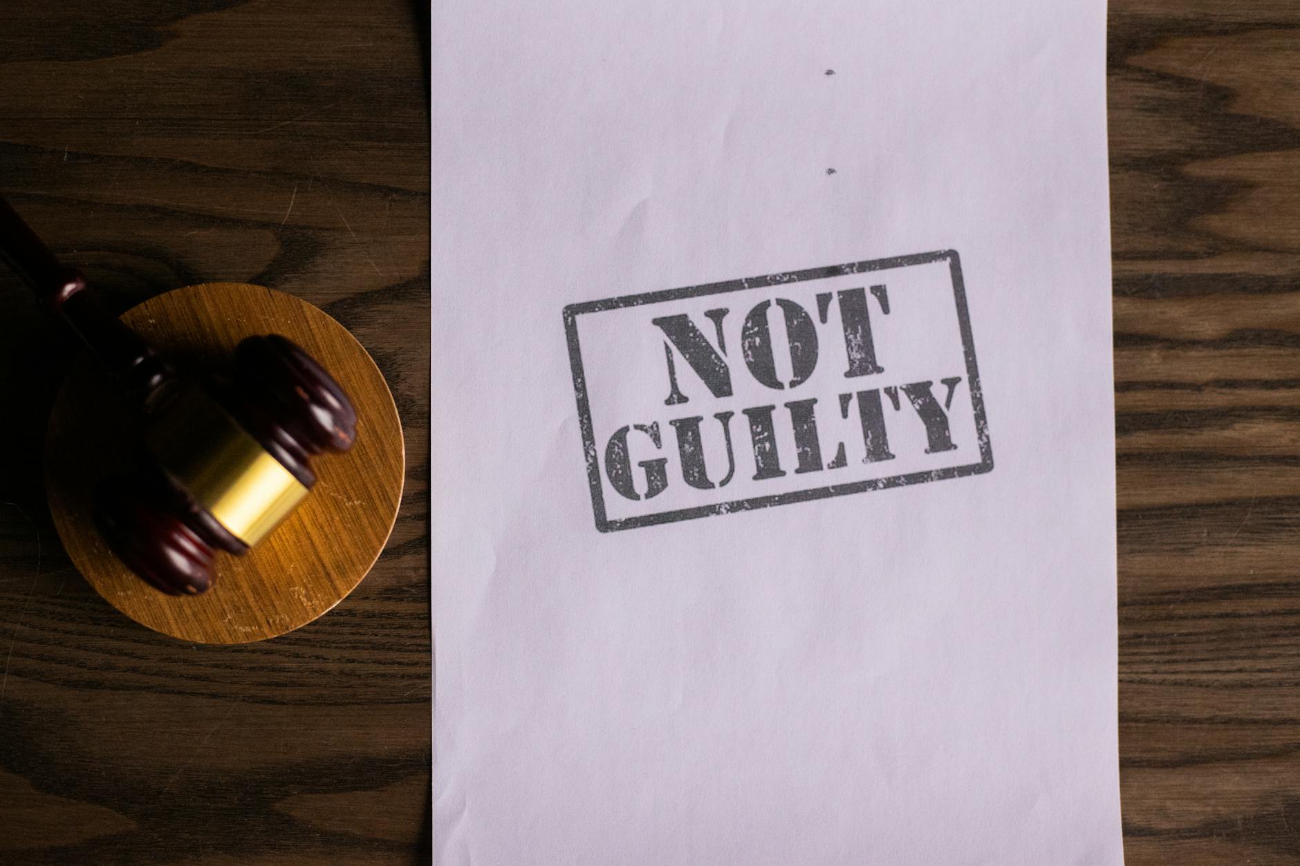 A courtroom document labeled 'Not Guilty' beside a gavel symbolizes justice.