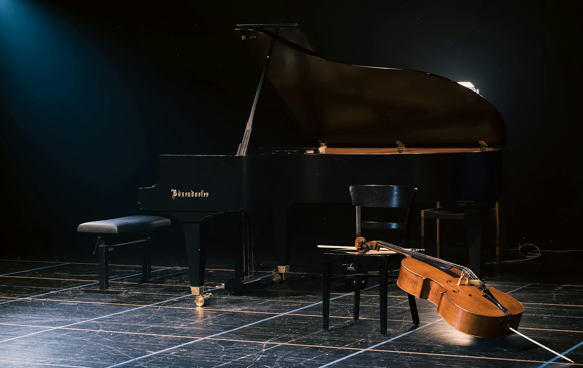 A grand piano and cello beautifully arranged on a dimly lit stage, capturing a serene musical moment.