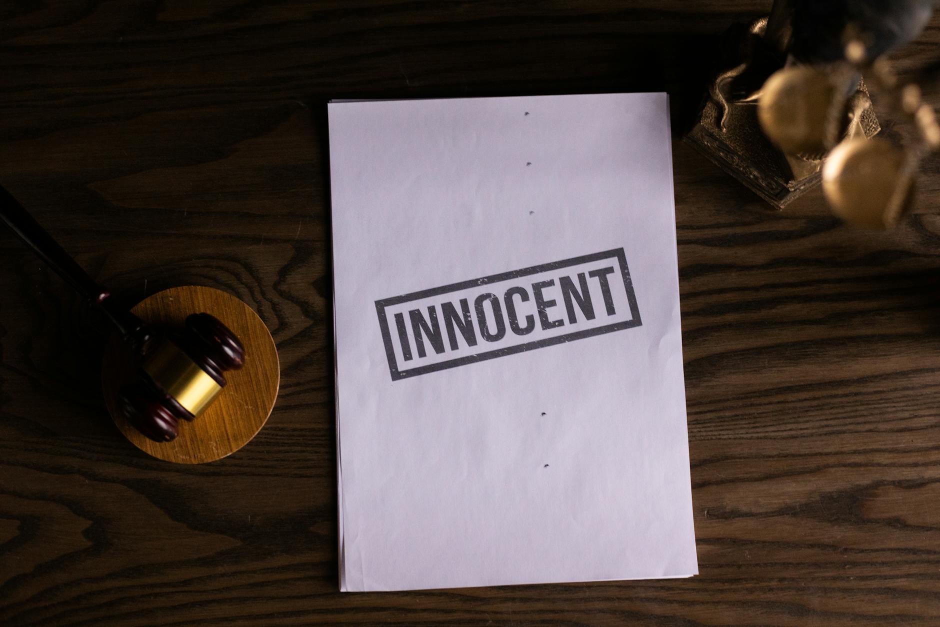 Close-up of legal document stamped 'Innocent' beside a gavel on a wooden desk.