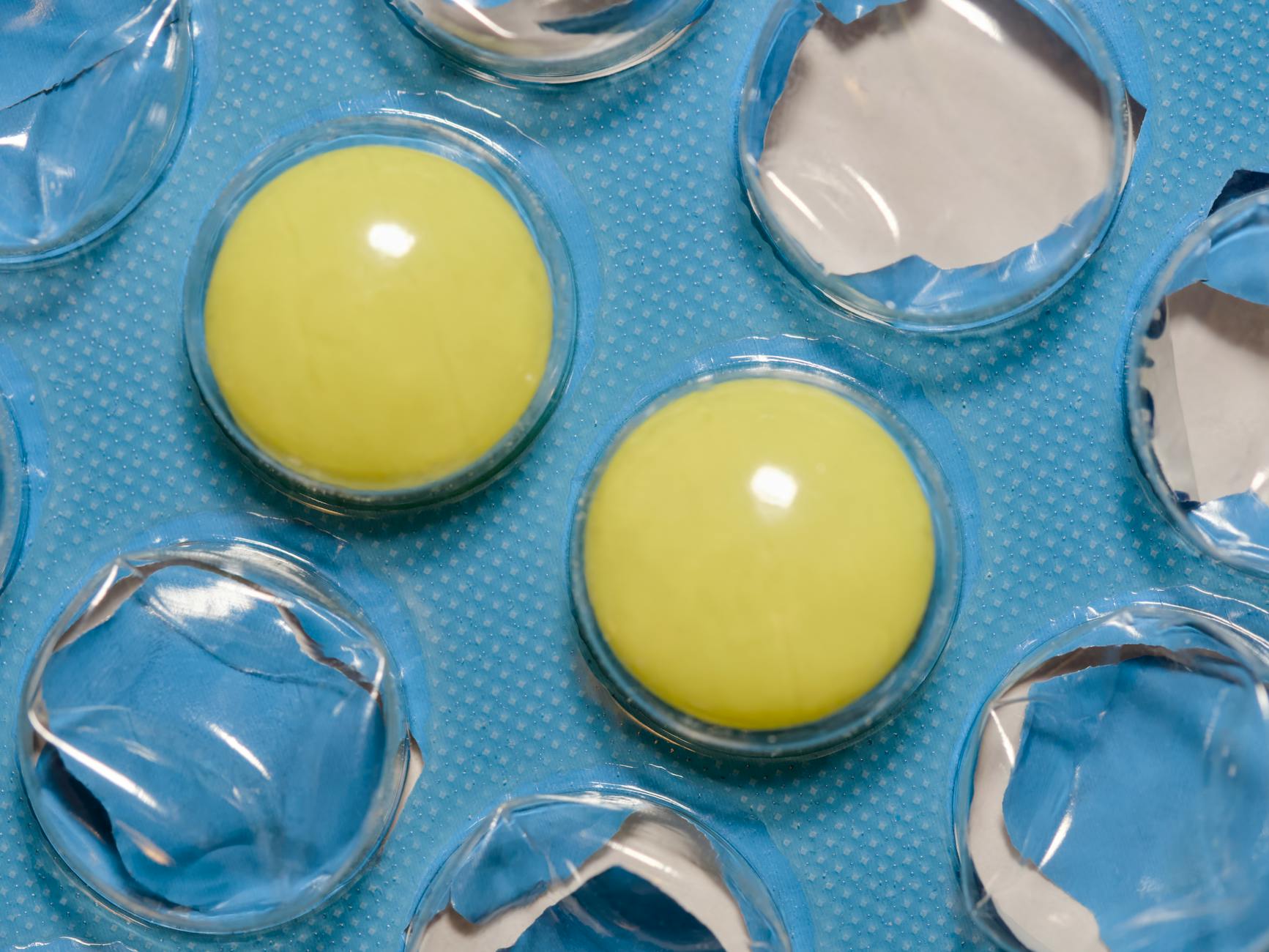 Close-up of yellow tablets in a blue blister pack, highlighting pharmaceutical and healthcare themes.