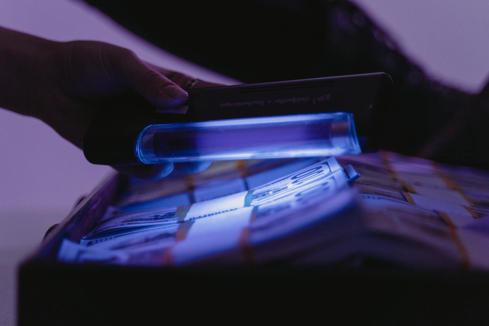 A close-up shot of banknotes under UV light to verify currency authenticity and detect counterfeits.