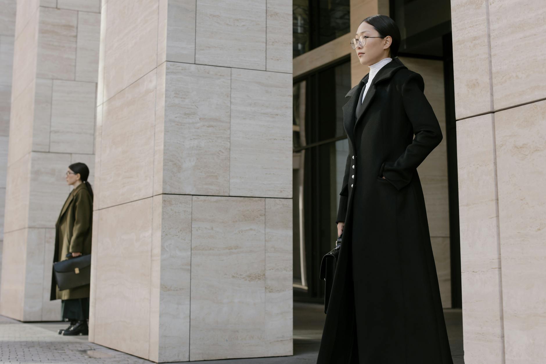 Two young professionals stand outside an office building, exuding confidence and style.